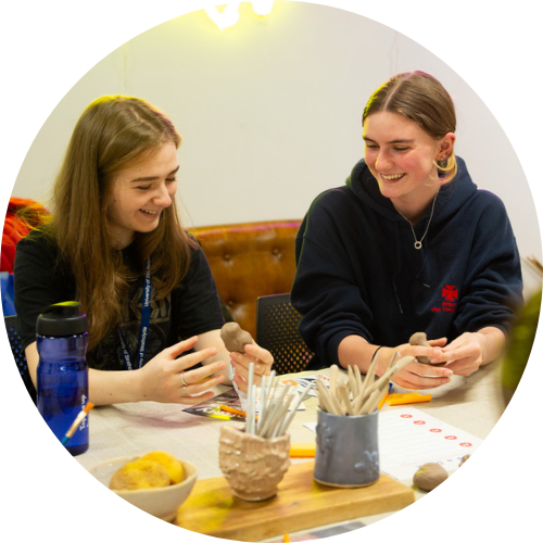 Two students at pottery class chatting together