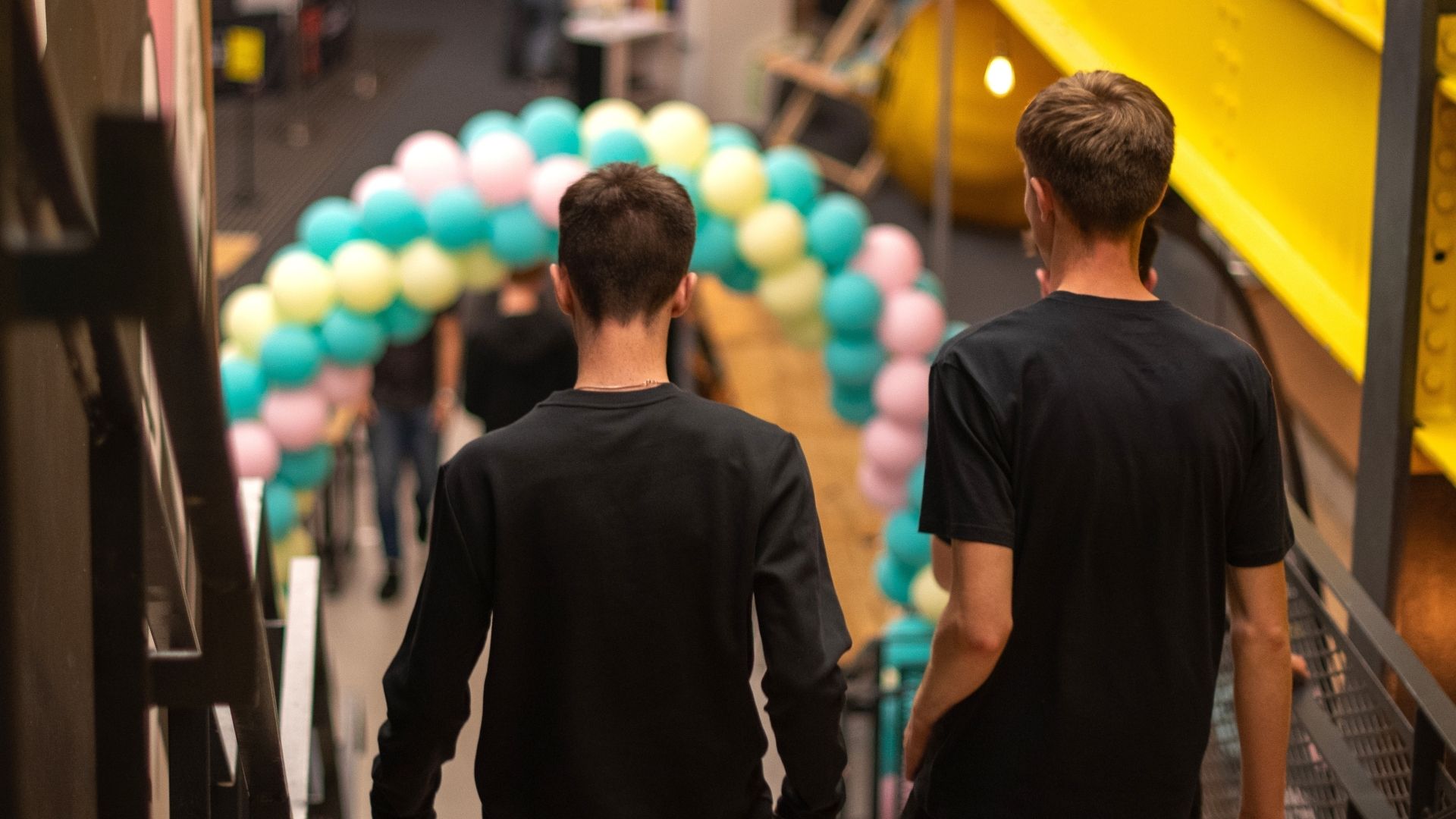 Two students walking down stairs in front balloon arch